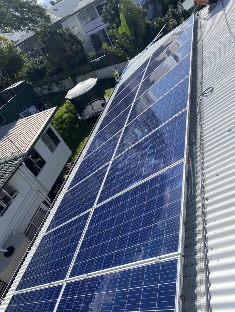 Solar panel bird proofing in Aspley: Blue solar panels with mesh edging on a white corrugated roof overlooking a backyard trampoline