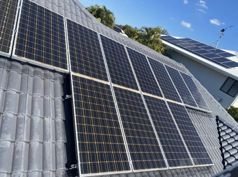 Solar panel bird proofing in Browns Plains: Mesh skirting around solar panels on a grey tile roof under a clear blue sky