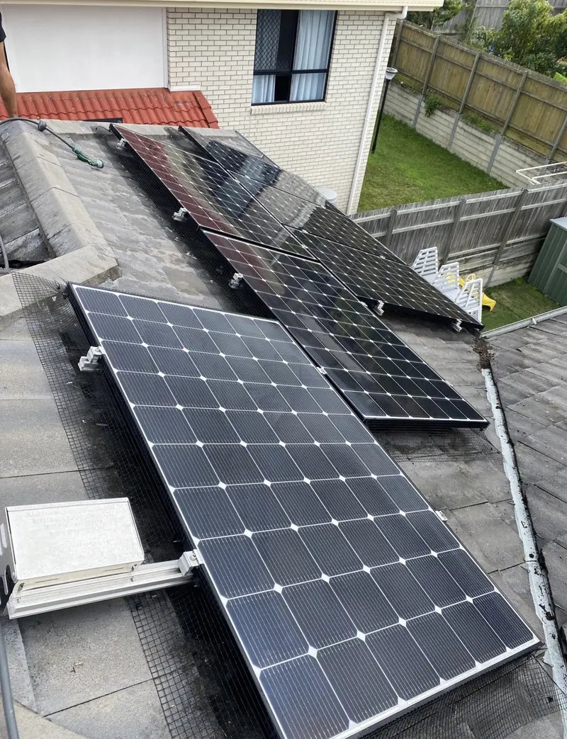 Solar panel bird proofing in Cannon Hill: Solar panels wrapped with mesh on a grey tile roof, dark debris piled along the edge