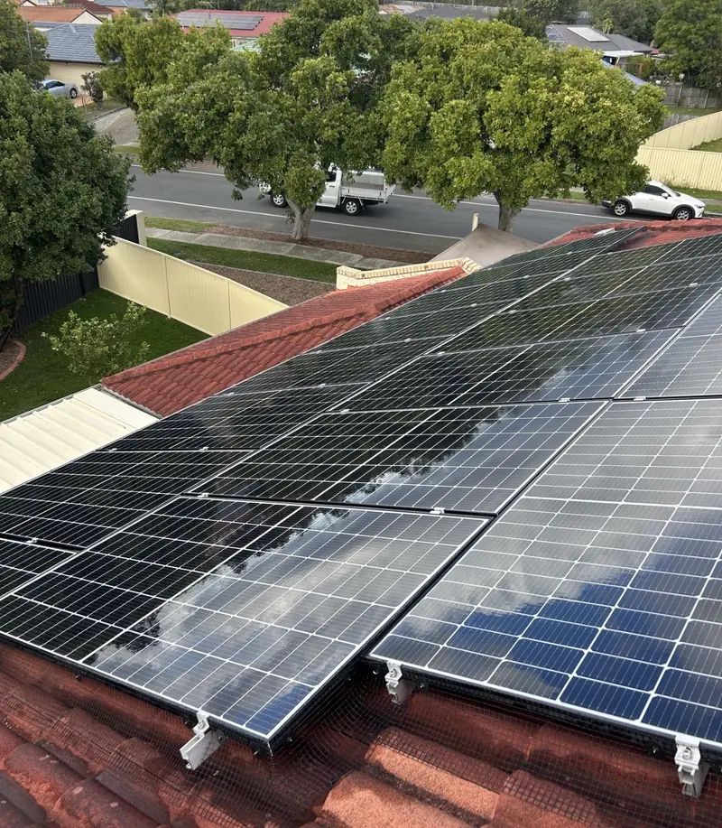 Solar panel bird proofing in Chermside: Large solar array with mesh and clips along its lower edge on a terracotta tile roof
