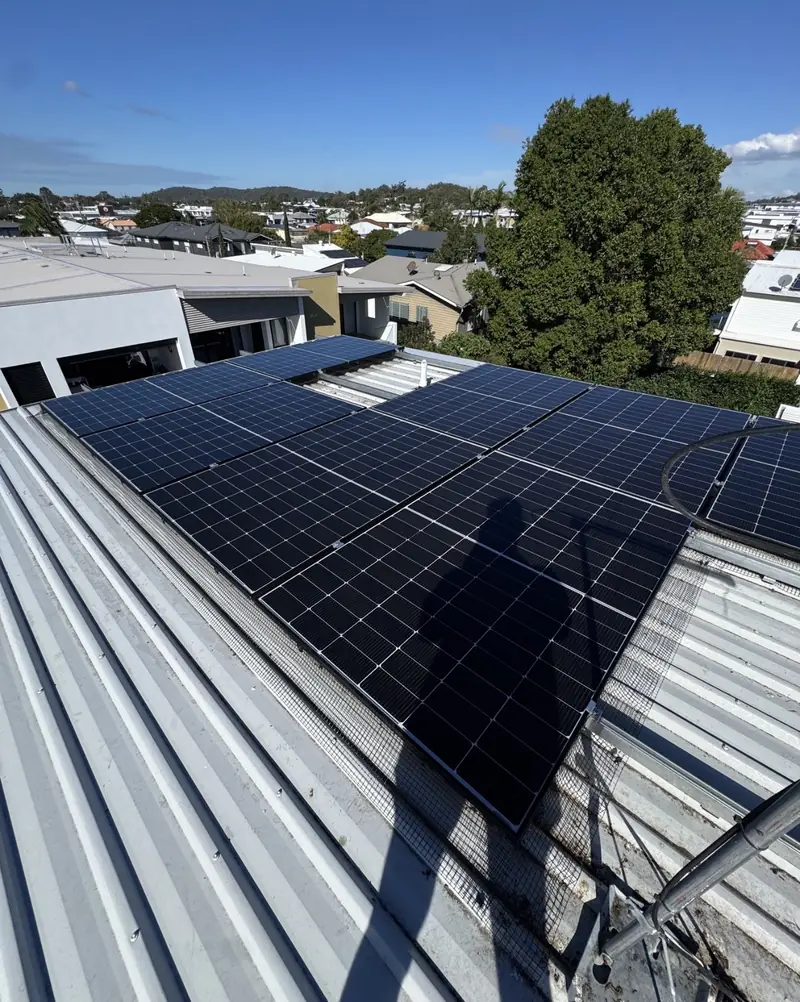 Solar panel bird proofing in Cleveland: Solar panels edged with mesh on a low-pitch silver metal roof overlooking suburban rooftops