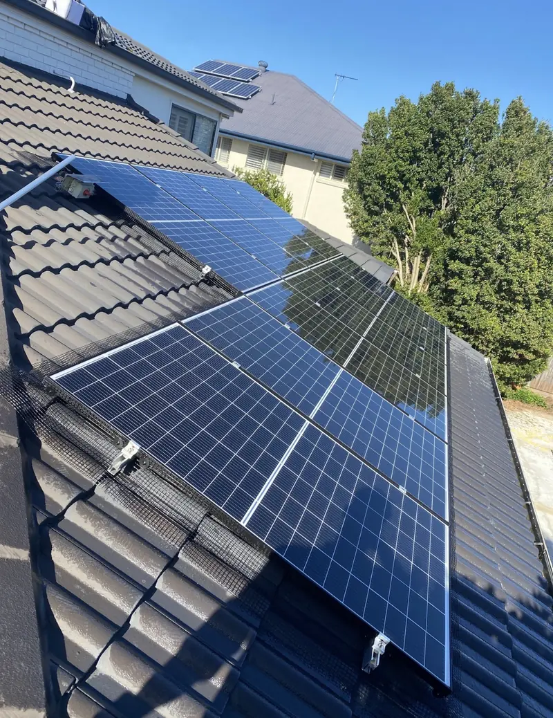 Solar panel bird proofing in Eight Mile Plains: Solar panels with black mesh edging on a dark charcoal tile roof beside a two-storey house