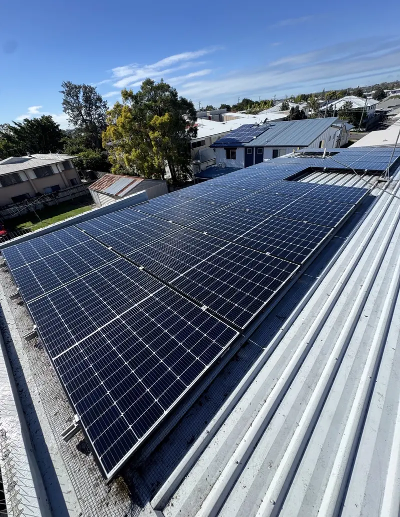 Solar panel bird proofing in Forest Lake: Mesh-edged solar panels on a silver corrugated metal roof with timber houses in the background