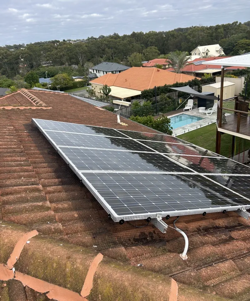 Solar panel bird proofing in Ipswich: Mesh clipped along solar panel edges on a weathered terracotta tile roof, backyard pool visible below