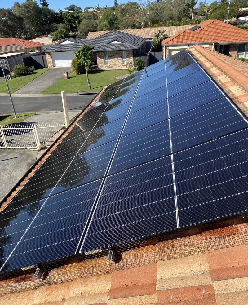 Solar panel bird proofing in Jindalee: Large black solar array with mesh along its lower edge on a sunny terracotta tile roof