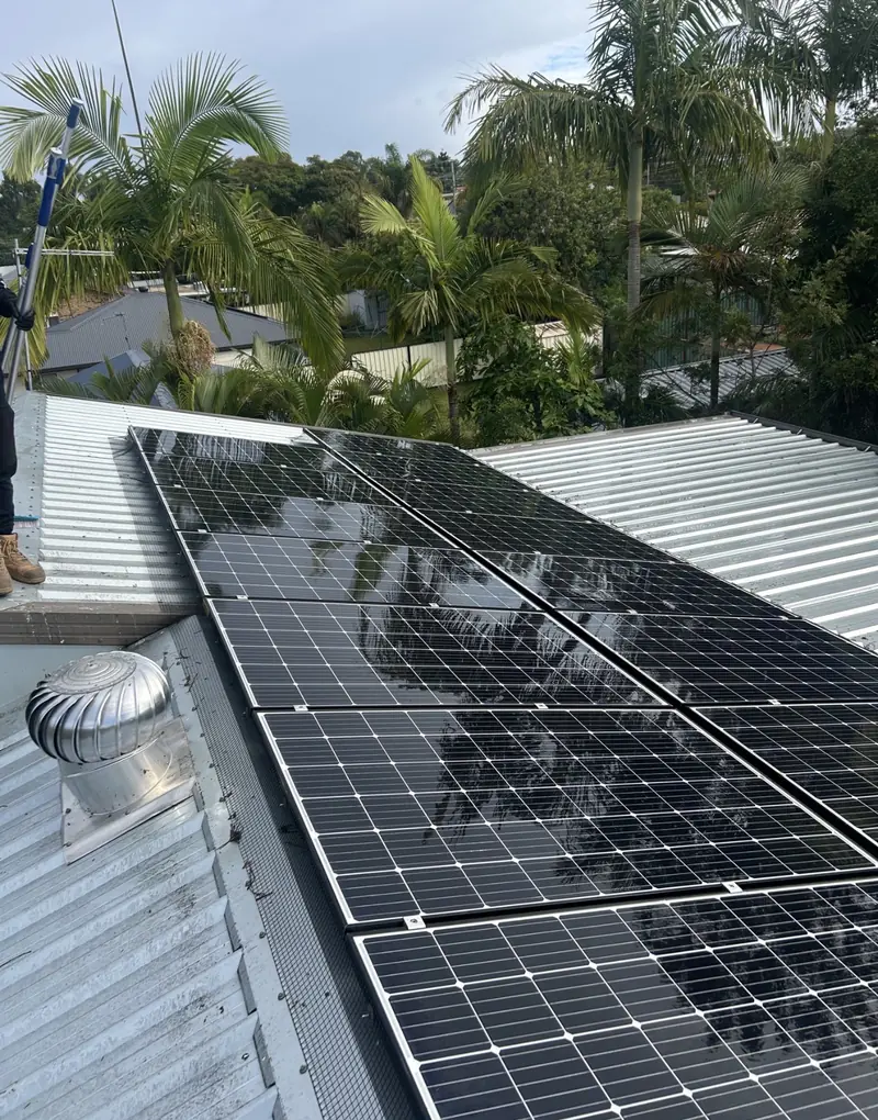 Solar panel bird proofing in Ripley: Black solar panels with mesh guard on a silver corrugated roof next to a whirlybird vent