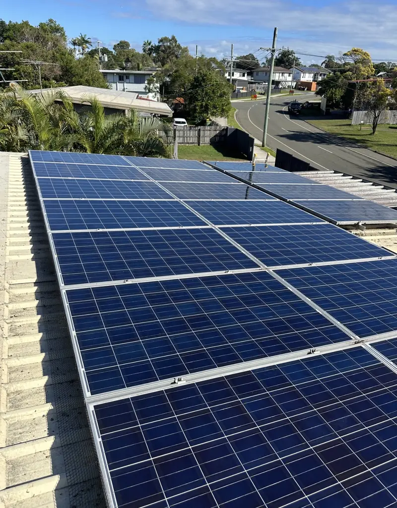 Solar panel bird proofing in Rochedale: Large blue solar array with edge mesh on a cream tile roof overlooking a suburban street