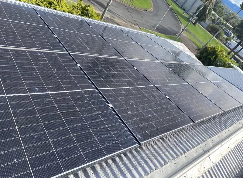 Solar panel bird proofing in Upper Mount Gravatt: Solar panels soiled with bird droppings, mesh edging visible, on a silver corrugated roof beside a road